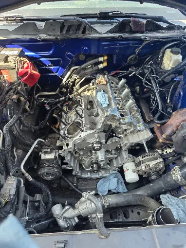 Open blue vehicle engine bay during mechanical work